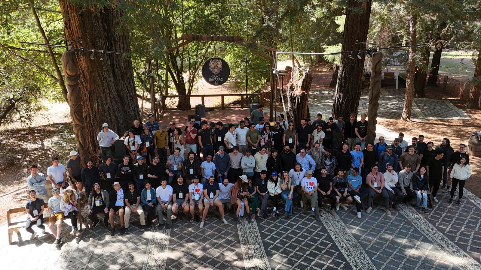 Group photo of Reboot 2025 attendees gathered under the redwoods at Camp Navarro