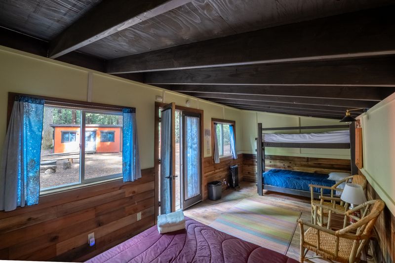 Inside a Camp Navarro cabin — bunk beds, wood-paneled walls, forest view