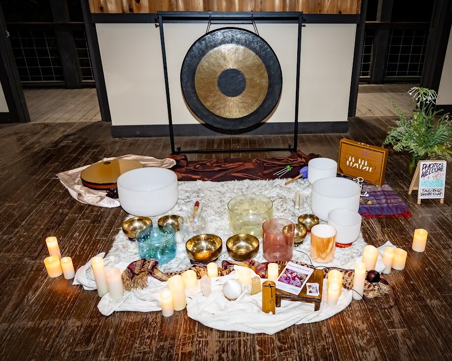 Crystal singing bowls, gong, and candles arranged for a sound bath